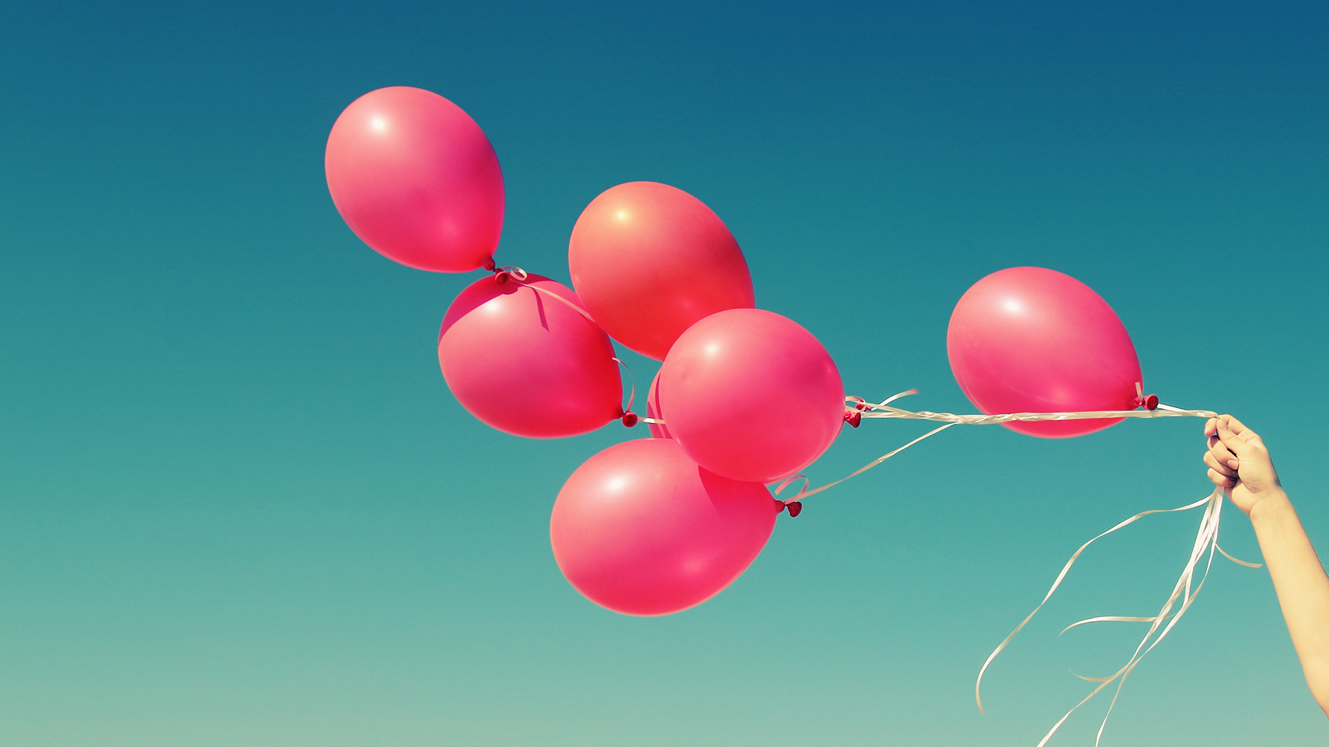 hand holding bunch of balloons